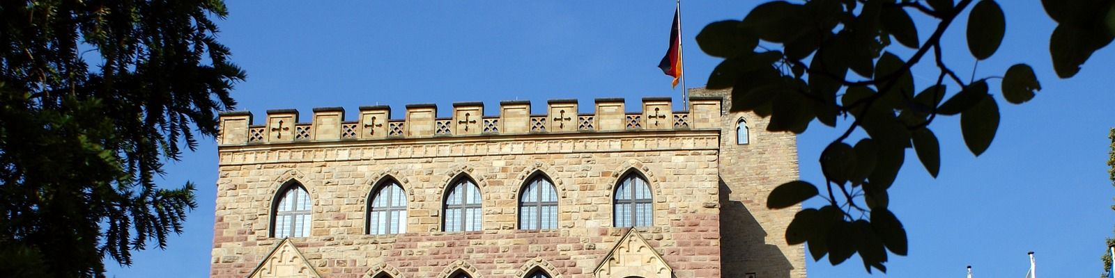 Das Hambacher Schloss in Neustadt an der Weinstraße mit Zinnen und schwarz-rot-goldener Fahne
