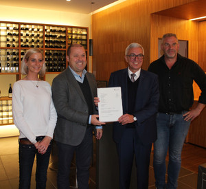 Ortsbürgermeister Benjamin Vrijdaghs (2.v.l.) und Innenminister Roger Lewentz (3.v.l.) bei der Übergabe des Förderbescheids im Rotweingut Jean Stodden.