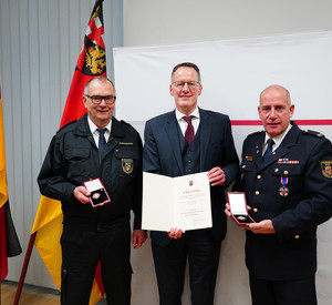 Innenminister Michael Ebling übergibt das Feuerwehr-Ehrenzeichen an Stefan Bohnenberger (l.) und Dirk Hargesheimer (r.). 
