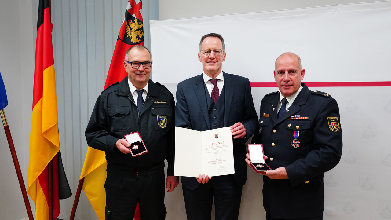 Innenminister Michael Ebling übergibt das Feuerwehr-Ehrenzeichen an Stefan Bohnenberger (l.) und Dirk Hargesheimer (r.). 