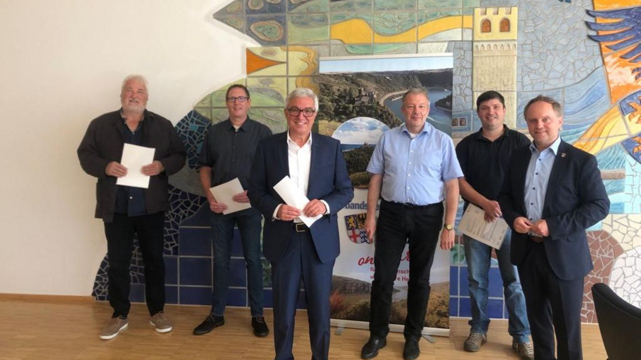 Donald Thomas (Ortsbürgermeister Dörscheid), Daniel Eschenauer (Erster Beigeordneter Prath), Innenminister Roger Lewentz, Mathias Schaefer (Ortsbürgermeister Dachsenhausen), Stefan Siering (Mitarbeiter der Verbandsgemeindeverwaltung Loreley) und Mike Weiland (Bürgermeister der Verbandsgemeinde Loreley) bei der Übergabe der Bescheide.