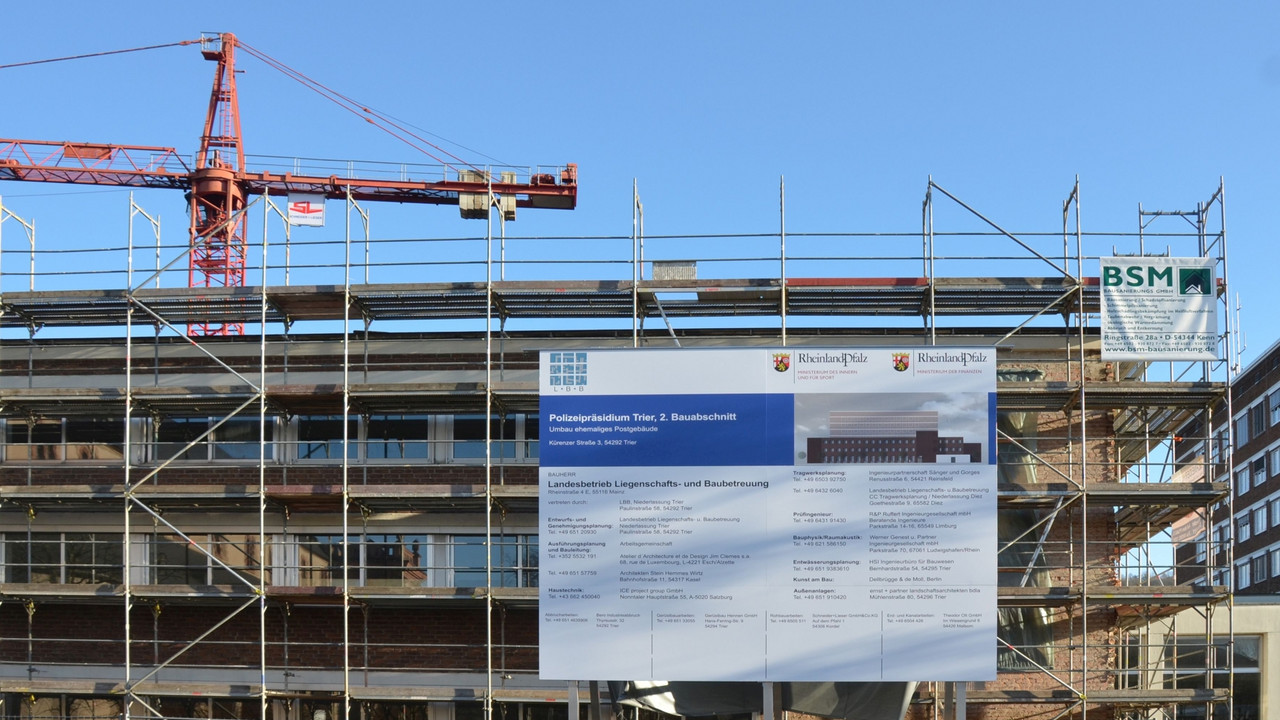 Bauschild an der Baustelle in Trier. Hinter dem Gebäude steht ein Kran