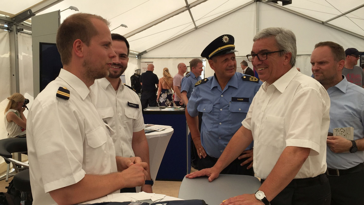 Minister Lewentz unterhält sich mit zwei jungen Männern in Uniform.