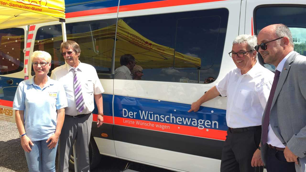 Minister Lewentz mit anderen vor dem Rettungswagen des ASB.