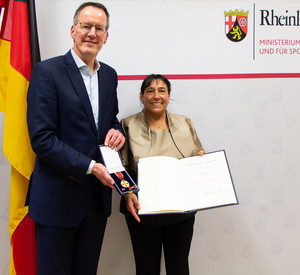 Innenminister Michael Ebling übergibt die Verdienstmedaille an Renate Stöber.