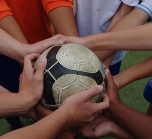 Sport zeigt, wie Integration geht. Viele Hände halten einen Fußball.