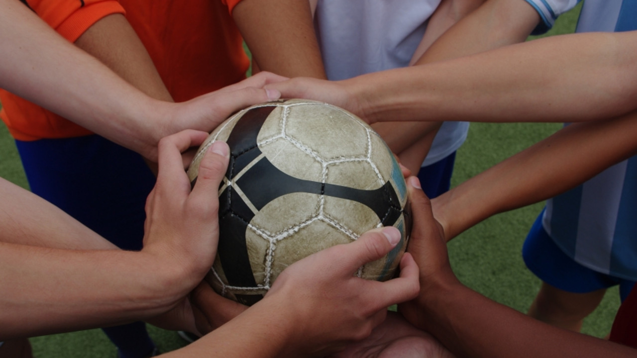 Sport zeigt, wie Integration geht. Viele Hände halten einen Fußball.