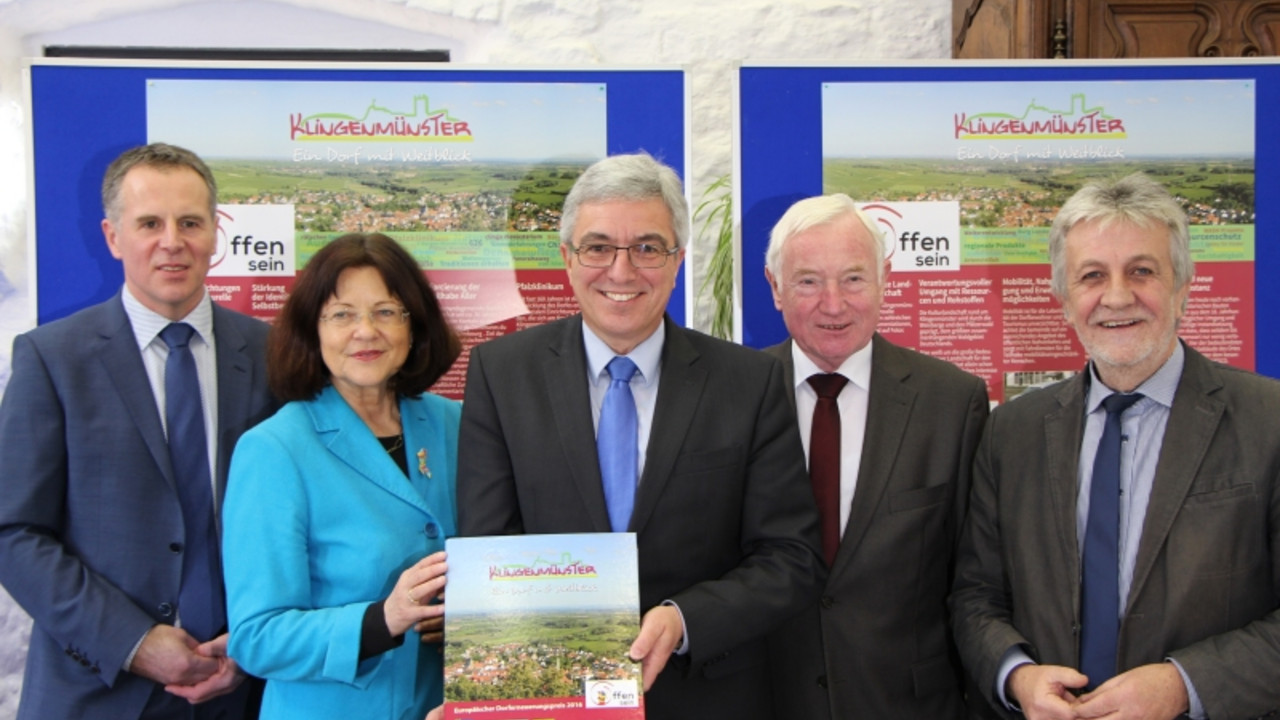 Klingenmünster tritt für Rheinland-Pfalz beim Europäischen Dorferneuerungspreis an. Auf dem Bild hält Innenminister Roger Lewentz die Bewerbungsunterlagen in die Kamera. Links von ihm stehen Landrätin Theresia Riedmaier und Herr Bauer; rechts von ihm stehen Bürgermeister von Klingenmünster Erwin Grimm und VG-Bürgermeister Hermann Bohrer