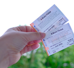 Frankfurt - May 2022: closeup female hands hold two tickets, monthly travel passes in germany for all modes of public transport in june, travel concept for country, in german: 9 euros - ticket 9-Euro-Tickets