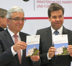 Minister Lewentz und der Leiter des Verfassungsschutzes RLP, Elmar May, halten jeweils einen Verfassungsschutzbericht in die Kamera