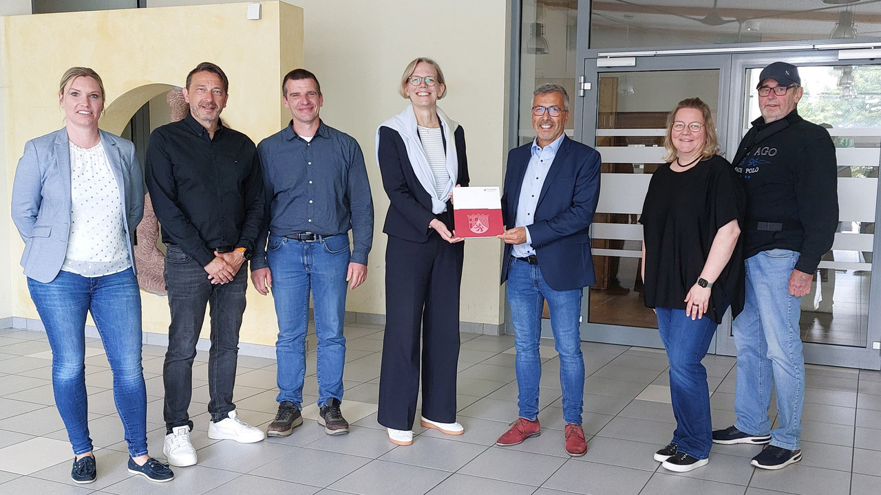 Staatssekretärin Simone Schneider (M.) überreicht dem Ortsbürgermeister von Schwegenheim, Andreas Weber (3. v. r.), einen Förderbescheid.
