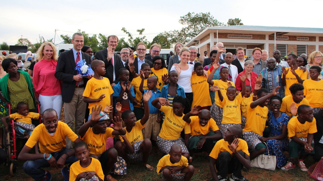 Gruppenfoto der rheinland-pfälzischen Delegation mit zahlreichen Kindern aus Ruanda. Alle winken in die Kamera.