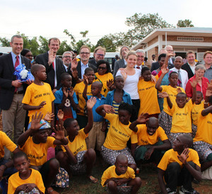 Gruppenfoto der rheinland-pfälzischen Delegation mit zahlreichen Kindern aus Ruanda. Alle winken in die Kamera.