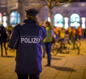 Eine Polizeibeamtin steht bei Nacht am Mainzer Hauptbahnhof. Im Hintergrund sind Menschen zu sehen.