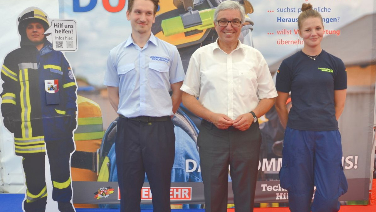 Minister Lewentz mit einer jungen Frau und einem jungen Mann vor der Feuerwehr und des THWs.