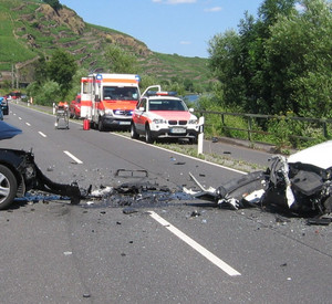 Verkehrsunfall mit zwei PKWs. Im Hintergrund stehen Rettungswagen bereit.