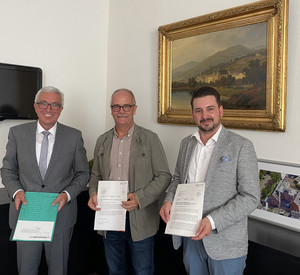 Innenminister Roger Lewentz (l.) übergibt das Aufnahmeschreiben im Beisein von Stadtbürgermeister Oliver Krügel (r.) an den VG-Beigeordneten Lutz Zaun (Mitte).