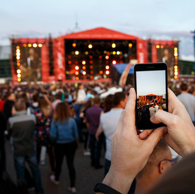 Eine Person filmt ein Open Air-Konzert mit dem Smartphone.