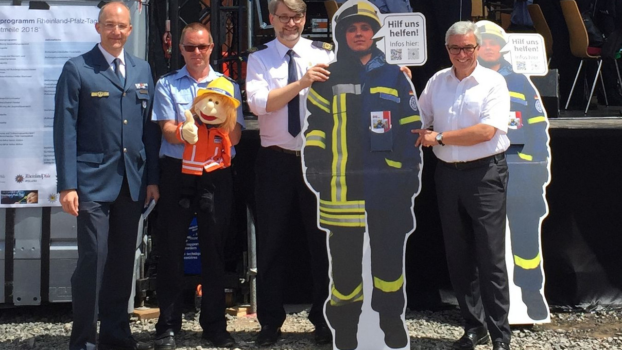 Minister Lewentz und andere mit einer lebensgroßen Pappfigur eines Feuerwehrmannes.
