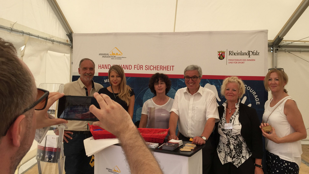 Minister Lewentz wird mit anderen am Stand der Kriminalprävention fotografiert.