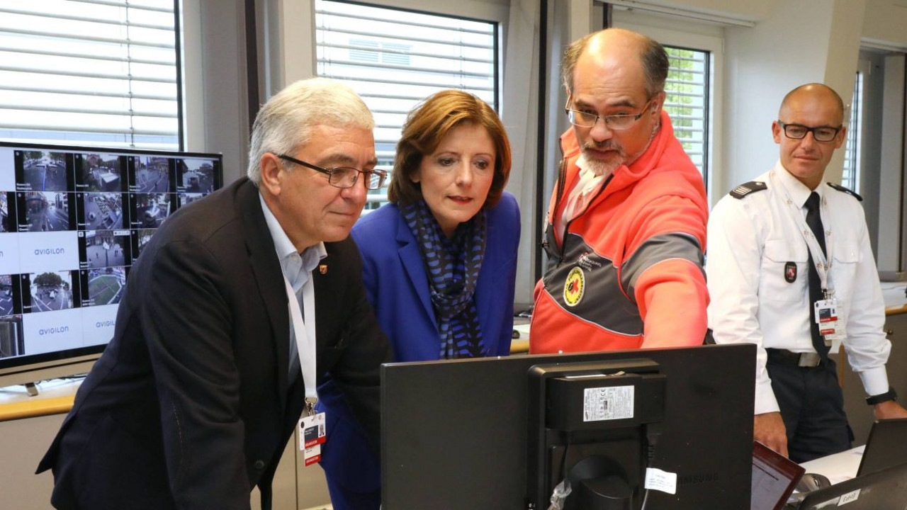 Innenminister Lewentz udn Ministerpräsidentin Malu Dreyer stehen vor einem Computer und blicken auf einen Bildschirm. Ein Mitarbeiter des Rettungsdienstes erläutert, was auf dem Bildschirm zu sehen ist.