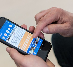 Eine Männerhand bedient ein Handy. Auf dem Bildschirm ist die Dorffunk-App zu sehen.