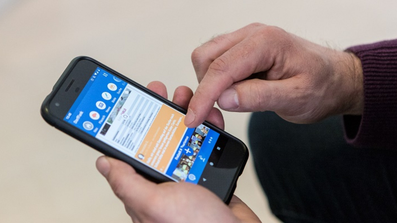 Eine Männerhand bedient ein Handy. Auf dem Bildschirm ist die Dorffunk-App zu sehen.