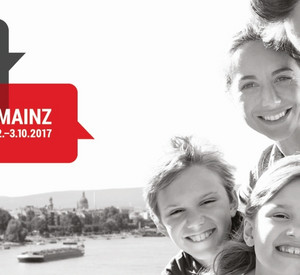 Schwarz-weiss-Selfie einer vierköpfigen Familie. Im Hintergrund ist die Stadt Mainz zu sehen. Links drei Sprechblasen in den Farben Schwarz, Rot, Gold. Jeweils in einer Blase die Texte: Zusammen sind wir Deutschland. Tag der Deutschen Einheit. Mainz 2.-3.10.2017