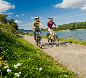 Zwei Fahrradfahrer unterwegs auf dem Radweg am Rhein.