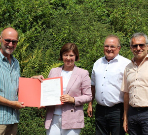 Staatssekretärin Nicole Steingaß mit Ortsbürgermeister von Rumbach, Ralf Weber (links), sowie dem dritten Kreisbeigeordneten Josef Bauer und dem Verbandsbürgermeister der VG Dahner Felsenland, Michael Zwick bei der Bescheidübergabe