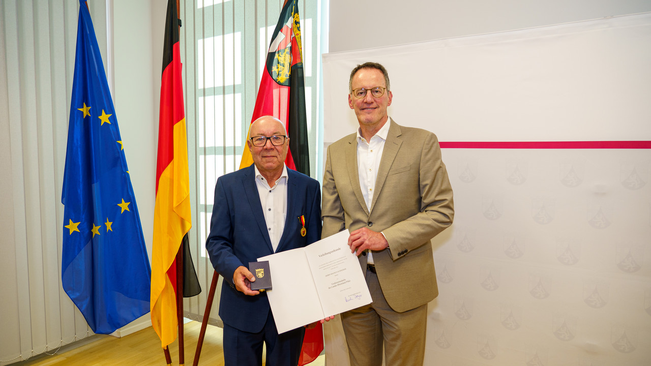 Minister Ebling überreicht die Landesverdienstmedaille an Magnus Schneider.