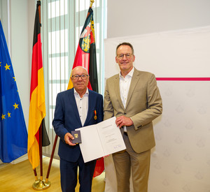 Minister Ebling überreicht die Landesverdienstmedaille an Magnus Schneider.