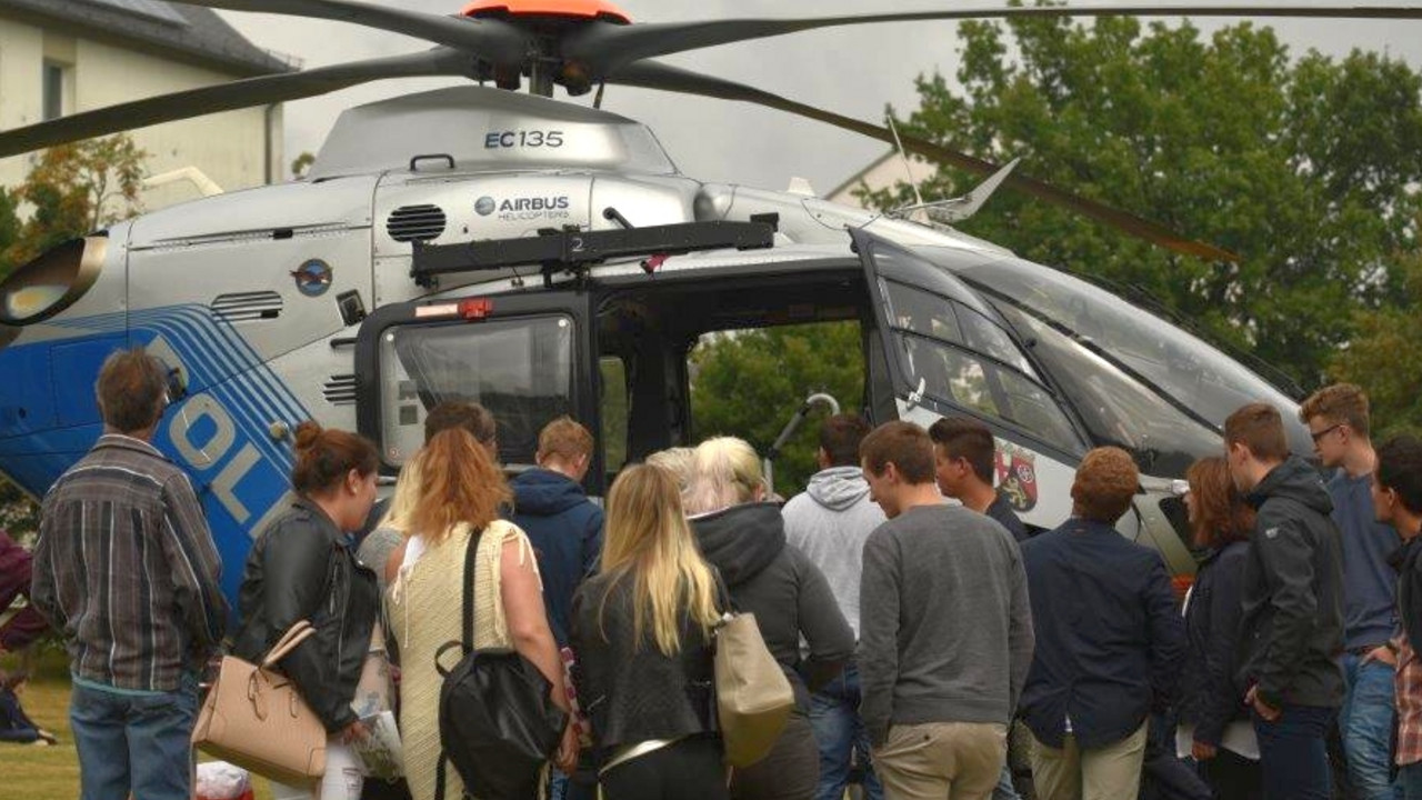 Eine Menschentraube sammelt sich vor einem Polzeihubschrauber, um ihn sich aus der Nähe anzusehen.