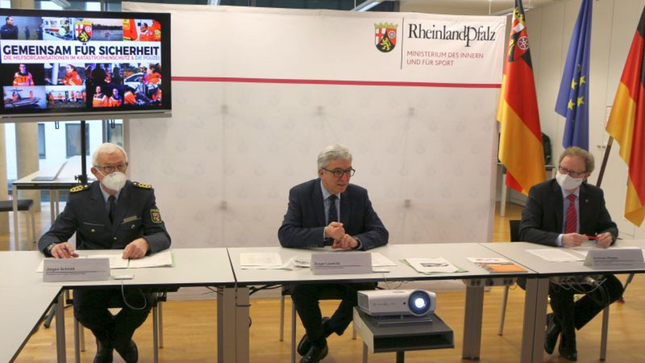 Innenminister Roger Lewentz mit zwei weiteren Personen an einem Tisch bei der Vorstellung eines Films "Gemeinsam für mehr Sicherheit"