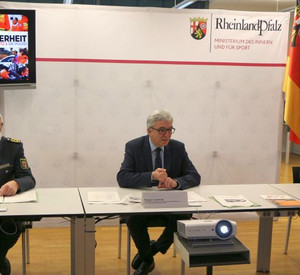 Innenminister Roger Lewentz mit zwei weiteren Personen an einem Tisch bei der Vorstellung eines Films "Gemeinsam für mehr Sicherheit"