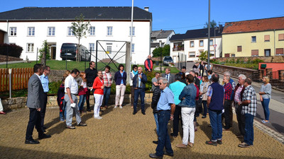 Die Jury des Dorferneuerungswettbewerbs versammelt sich auf einem Dorfplatz