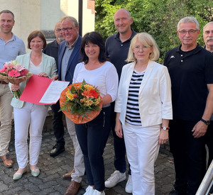 Staatssekretärin Nicole Steingaß (2.v.r.) und Ortsbürgermeister Manfred Klasen (4.v.r.) bei der Übergabe des Förderbescheids in Lasel. 