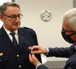Roger Lewentz steckt Michael Hopp das Ehrenzeichen der Feuerwehr an