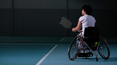 Eine Rollstuhltennisspielerin auf dem Court kurz vor dem Aufschlag.