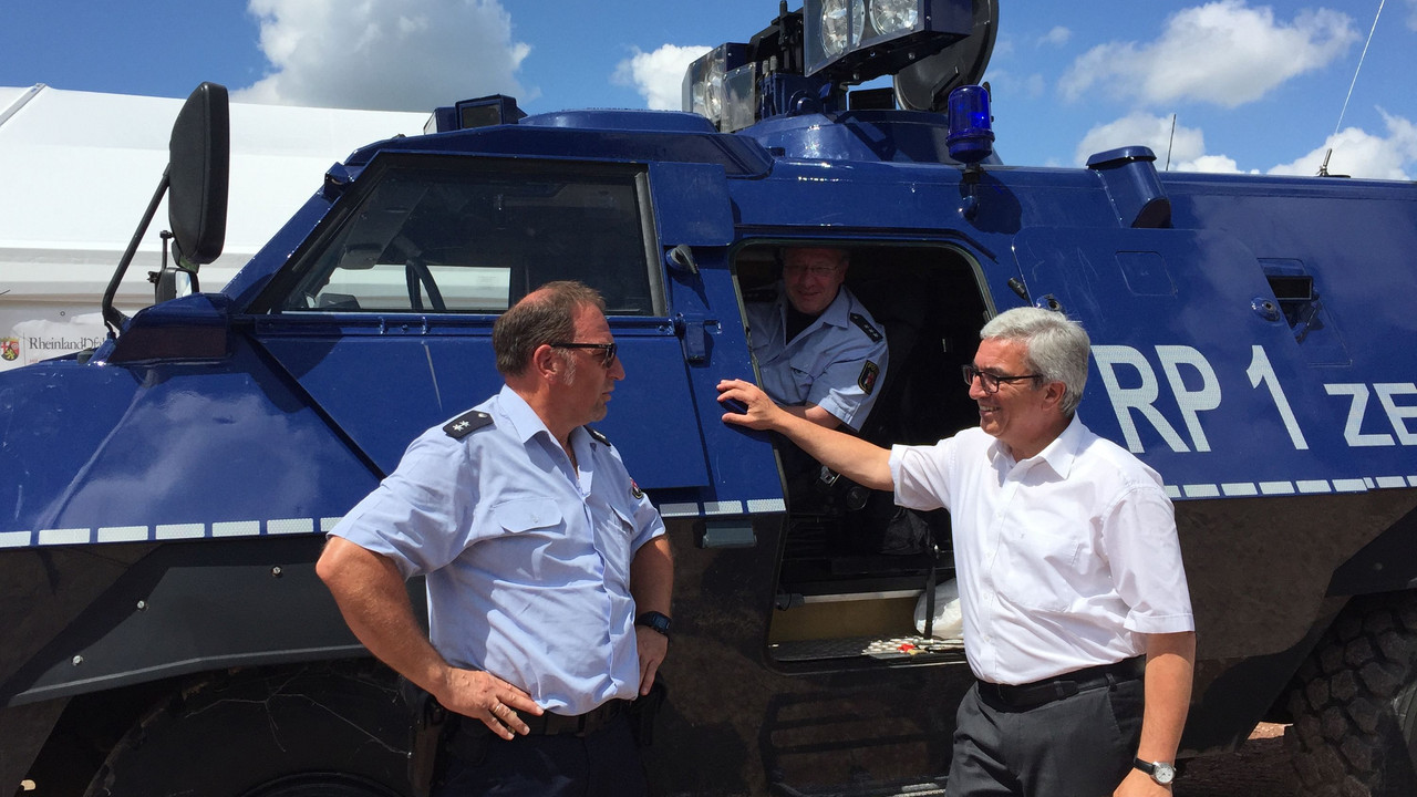 Innenminister Roger Lewentz steht mit einem Polizeibeamten vor einem Fahrzeug des THW.