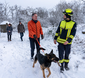 Innenminister Michael Ebling mit einem Rettungshund und einem Rettungshunde-Führer.
