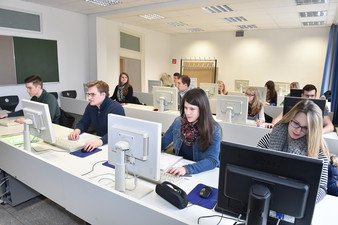 Junge Menschen in einem Klassenraum mit EDV-Ausstattung